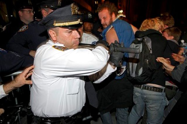 A police officer uses his baton against protestersâand, apparently, media